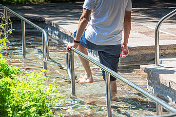 Ein Mensch mit kurzer Hose tritt im Storchengang ins Wasser.