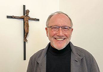 Portrait von Pater Karl Kern mit Kreuz im Hintergrund