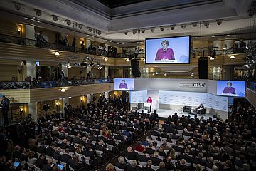 Großer Saal mit vielen Menschen an Tischen, vorne spricht Bundeskanzlerin Angela Merkel, Bild von der Sicherheitskonferenz 2019