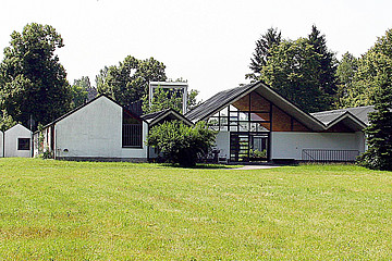 Eine Ansammlung einstöckiger Gebäude auf grüner Wiese mit spitzen Dächern.