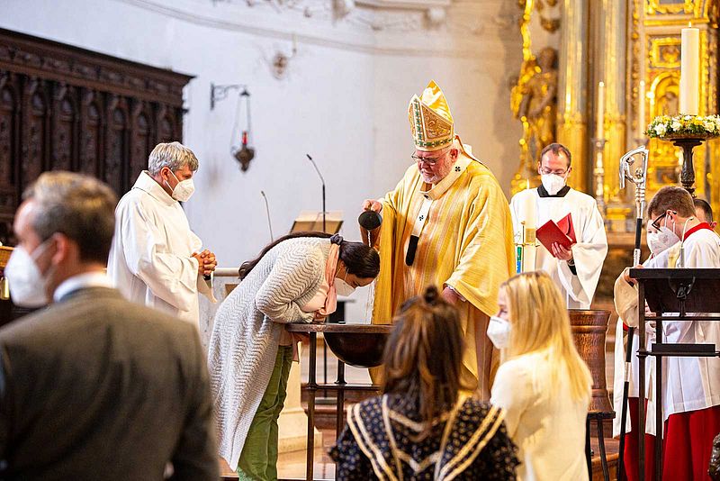 Kardinal Marx tauft eine Frau in der Münchner Jesuitenkirche Sankt Michael.