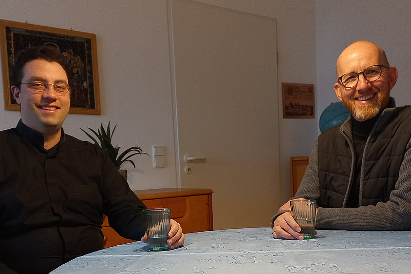Die Priester Manuel Kleinhans (links) und Klaus Hofstetter (rechts) sitzen an einem Tisch in ihrer WG.