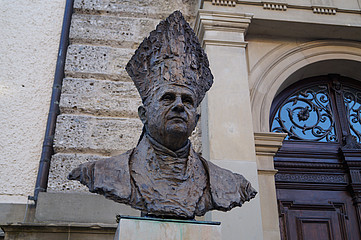 Die brozene Büste des emeritierten Papstes Benedikt XVI. auf ihrem Sockel vor der Kirche St. Oswald in Traunstein.