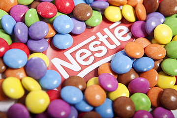 Nestle-Logo umrahmt von bunten Schokolinsen