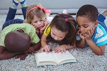Vier Kinder lesen zusammen ein Buch